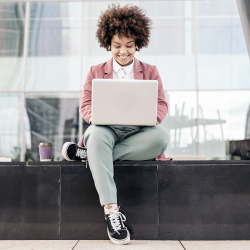 Woman sitting outside her office while working on her computer