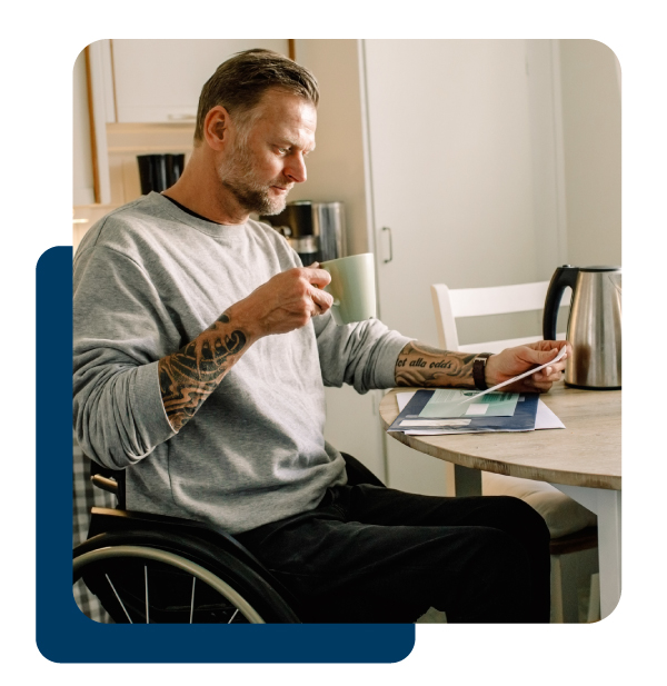 Man in wheel chair reading mail and drinking coffee