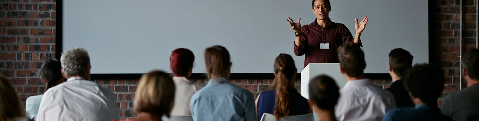 Person giving a lecture in front of a crowd. 