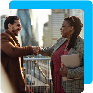 Woman and man shaking hands with a city-scape in the background.