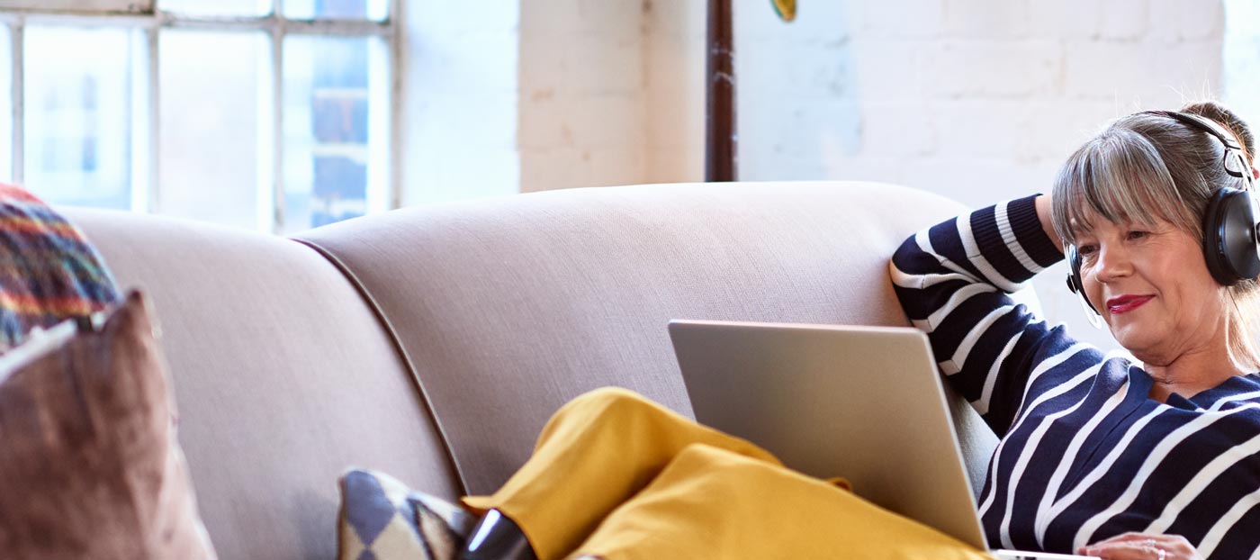 Woman laying on couch watching online webinar