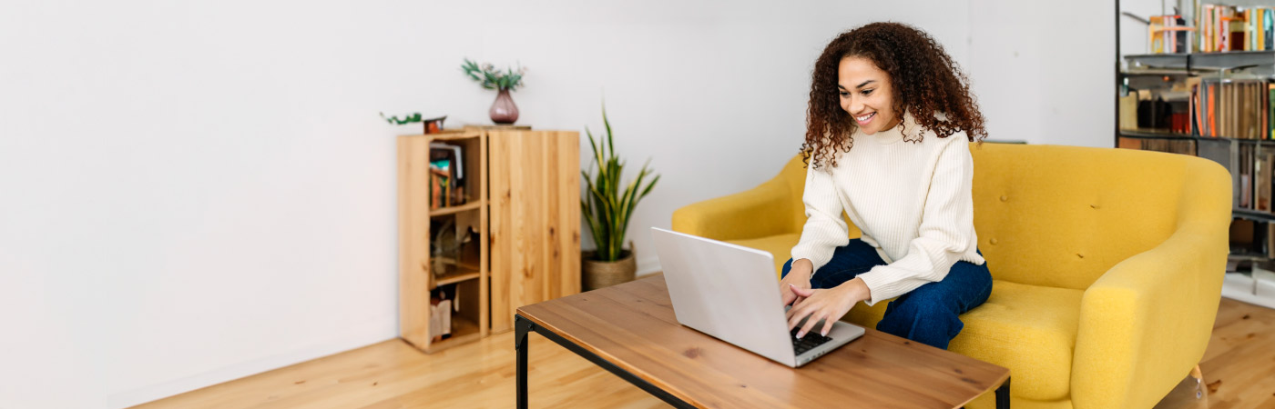 emerging leader working on their computer while sitting on a yellow couch