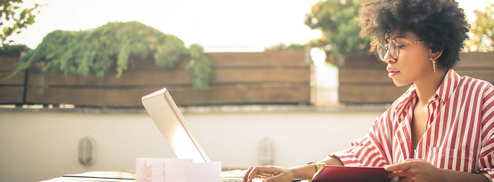 A woman working with DonorPerfect on her laptop while sitting outside.