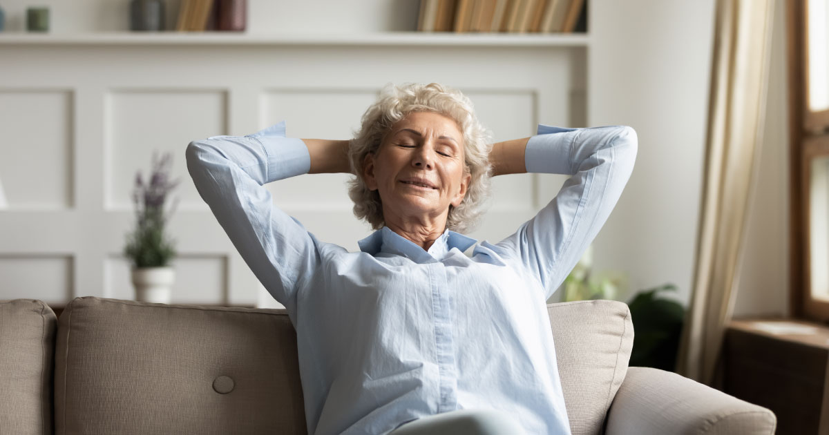 Calm senior 60s woman sit relax on comfortable sofa in living room taking nap or daydreaming at home, happy mature 70s grandmother rest on couch breathing fresh air, elderly stress free concept